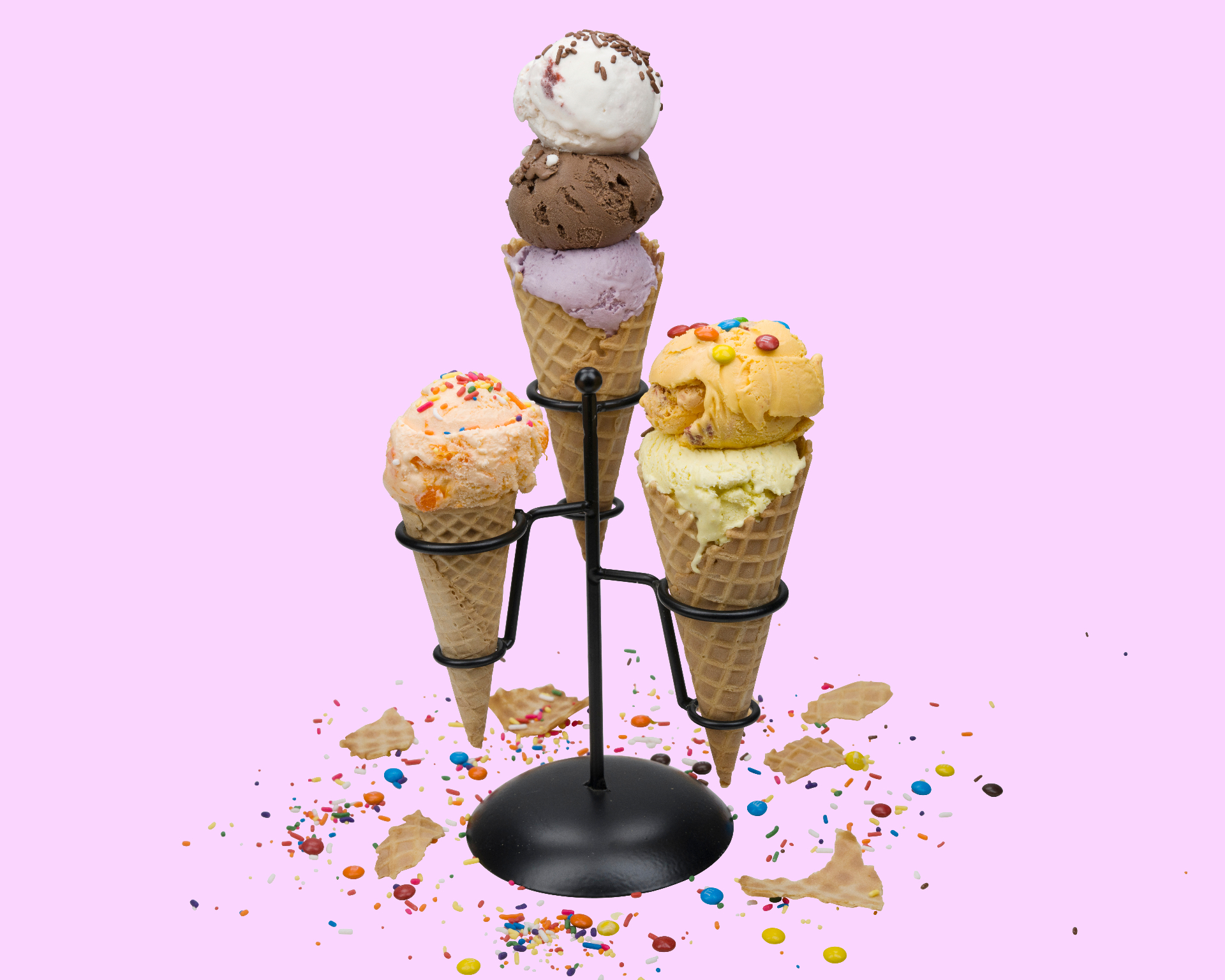 A trio of waffle cones with colorful scoops, sprinkles and candies